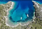 Datça Akvaryum Koyu havadan panoramik görünümü ve turkuaz denizde süzülen tekneler.